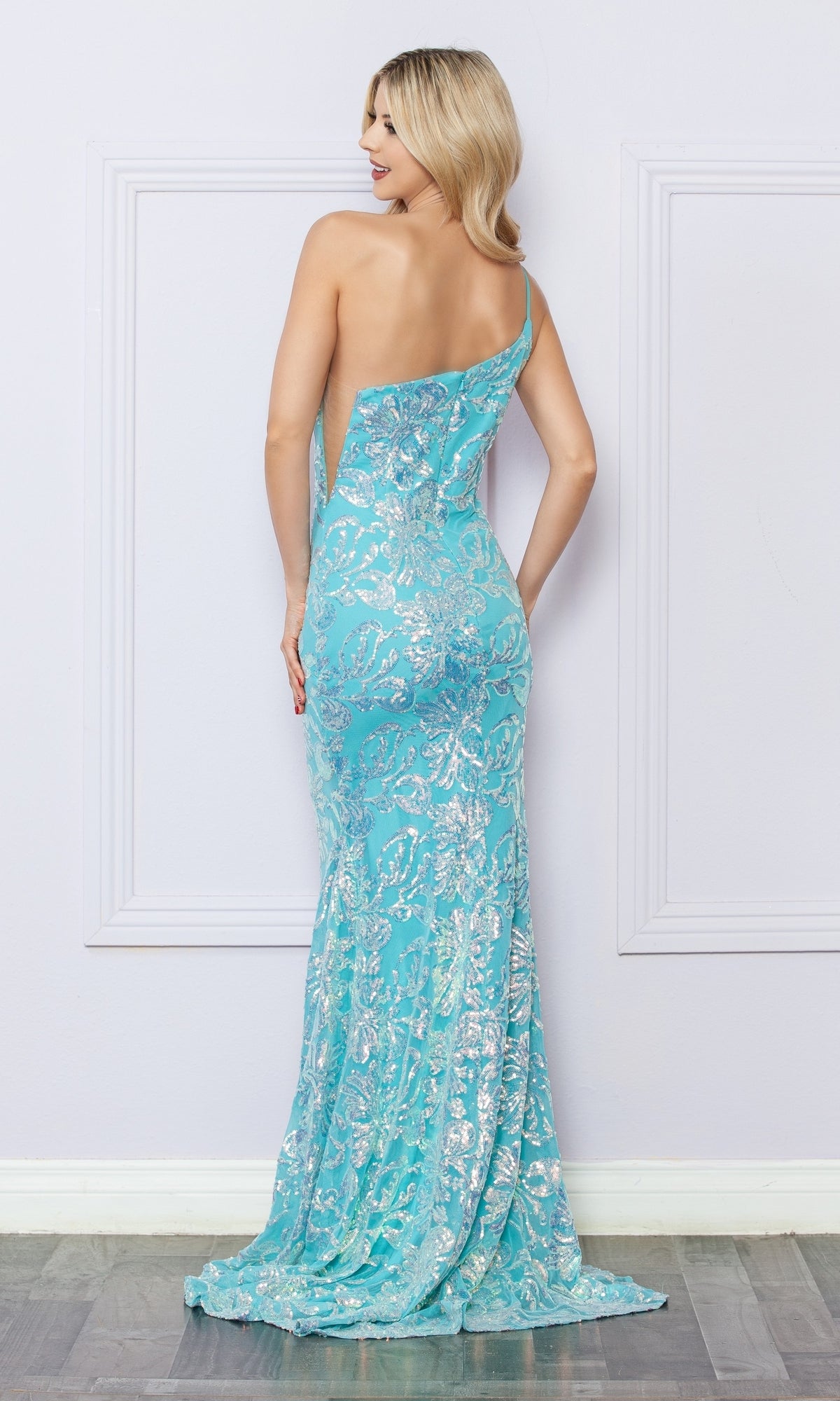 A woman stands with her back to the camera, wearing the One-Shoulder Long Sequin-Print Prom Dress R1308 in light blue with silver floral patterns, against a light-colored wall.